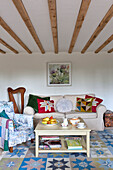 Patchwork cushions on sofa with harp in beamed living room of Essex home, England, UK