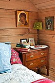 Bücher auf einer Holzkommode am Bett eines holzverkleideten Hauses in Essex, England, Vereinigtes Königreich