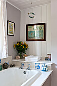 Cut flowers and ornaments with artwork, bathroom detail, Essex home, England, UK