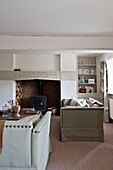 Vernietete Sofas und Holzofen im Wohnzimmer eines Hauses in Buckinghamshire, England, Vereinigtes Königreich