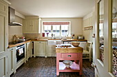 Fitted kitchen with original brick floor and pink butches block in Buckinghamshire home, England, UK