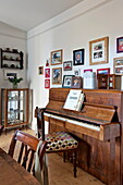 Familienfotos an der Wand über dem Klavier in einem Haus in Bovey Tracey, Devon, England, UK