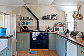Türkisfarbene Schränke mit marineblauem Herd in der Küche eines Bauernhauses in Suffolk, England, UK