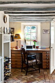 Stuhl am Schreibtisch mit Weinregal und Backsteinboden in einem Bauernhaus in Suffolk, England, UK