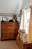 Vintage wooden chest at bedroom window in Suffolk farmhouse, England, UK