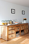 Storage jars and cut roses on wooden sideboard in Wadebridge home, Cornwall, England, UK