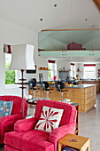 Pink matching armchairs in open plan kitchen living room of contemporary home, Cornwall, England, UK