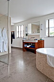 Bathrobes hang in spacious wet room with shower screen in contemporary home, Cornwall, England, UK