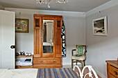 Antiker hölzerner Kleiderschrank und Kunstwerke im Schlafzimmer eines Cottage in Padstow, Cornwall, England, Vereinigtes Königreich