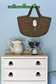 Shopping bag hangs above white painted drawers in Padstow cottage bedroom, Cornwall, England, UK