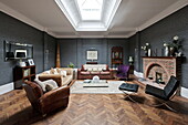 Brown leather armchair and sofa with Barcelona chair and footstool in living room with parquet flooring, London home, England, UK