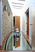 Girl playing on glass floor in hallway of contemporary London home, England, UK