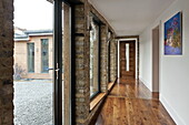Wooden hallway with view through windows to gravel terrace in London home, England, UK