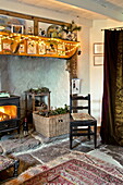 Fairylights and Christmas cards at hearth of wood burning stove in farmhouse, Cornwall, England, UK