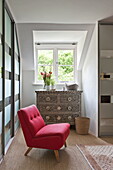 Roter Sessel mit eingelegter Kommode in einem modernen Haus in Suffolk/Essex, England, Vereinigtes Königreich