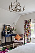 Colourful floral curtains with blue dressing table in bedroom of contemporary Suffolk/Essex home, England, UK