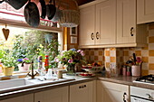 Abtropffläche am Fenster einer Küche mit weißen Einbaugeräten und karierter Spritzwand in einem Haus in London, England, UK
