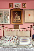 Messingbett und Kunstwerke im rosa Schlafzimmer eines Londoner Hauses, England, UK