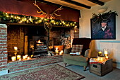 Fairylights and lit candles in exposed brick fireplace in Shropshire cottage, England, UK