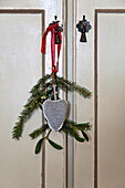 Heart shaped decoration with sprig of mistletoe and pine on cupboard door in Shropshire cottage, England, UK