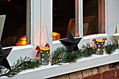 Lit candles and Christmas decoration on windowsill of Shropshire cottage, England, UK