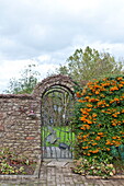 Arched garden gate in farmhouse garden, Blagdon, Somerset, England, UK