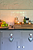Lit tealights with apples and nuts on grey kitchen worktop with silver hearts in Tregaron home Wales UK