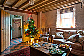 Beleuchteter Weihnachtsbaum im Wohnzimmer mit Balken in Tregaron, Wales, Vereinigtes Königreich