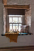 Tartan cushion and blanket on window seat in Tregaron home Wales UK
