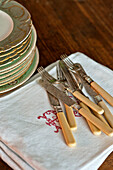 Silver cutlery with bone handles and china plates with napkins in Sherford barn conversion Devon UK