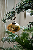 Gold metallic bauble on Christmas tree in Crantock home Cornwall England UK
