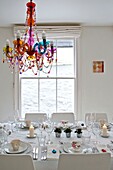 Beaded glass chandelier above dining table with sash window in Penzance family home Cornwall England UK