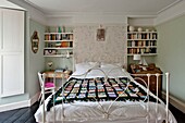 Black crochet blanket on double bed with bookshelves in Penzance family home Cornwall England UK