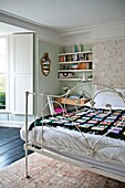 Black crochet blanket on double bed with bookshelf in Penzance family home Cornwall England UK