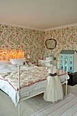 White dress and dollshouse in girl's room with pink floral wallpaper in Penzance family home Cornwall England UK