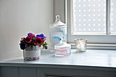 Glass storage jars with pansies in bathroom of Penzance family home Cornwall England UK