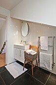 Weißes Badezimmer mit Korb auf einem Stuhl in einem Einfamilienhaus in Wadebridge, North Cornwall, UK