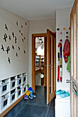 Flock of birds flying in hallway above plastic storage boxes in hallway of modern family home Cornwall UK