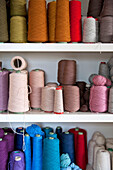 Assorted spools of wool on white shelving unit Cornwall UK