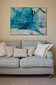 Light grey sofa below modern artwork in living room of family home, Cornwall, UK