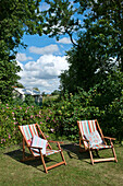 Two striped deck-chairs in back garden under cloudy sky
