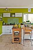 Frühstücksbar aus Holz und Metzgerblock in der lindgrünen offenen Küche eines Familienhauses in East Grinstead, West Sussex England UK