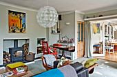 Große Pendelleuchte im Wohnzimmer mit rot gestrichenem Stuhl und Kaminofen East Grinstead Familienhaus West Sussex England UK