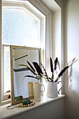 Dried grasses in ceramic jug with mirror on windowsill in Stamford home Lincolnshire England UK