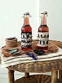 Fabric covered bottles and cake cases with coloured yarn on wicker side table London England UK