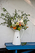Cut flowers in white jug on blue bench seat outside Cambridge cottage England UK