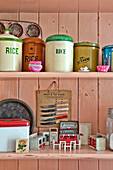 Rice storage tins with dolls house furniture on painted dresser in Cambridge cottage England UK