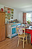 Vintage advertising above salvaged sideboard and kitchen table in Cambridge cottage England UK