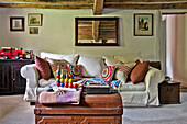 Child's toys on travelling trunk with white sofa in beamed living room of Cambridge cottage England UK