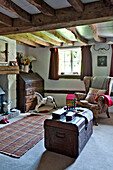 Ohrensessel und alte Truhe mit Schaukelpferd im Wohnzimmer eines Cottage in Cambridge England UK